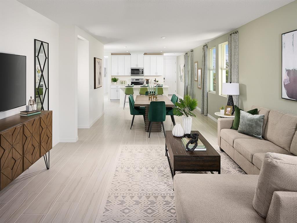 An open-concept living and dining area features light tile floors, a modern kitchen, and furniture — 3960 GIORGIO DRIVE, WINTER HAVEN, FL