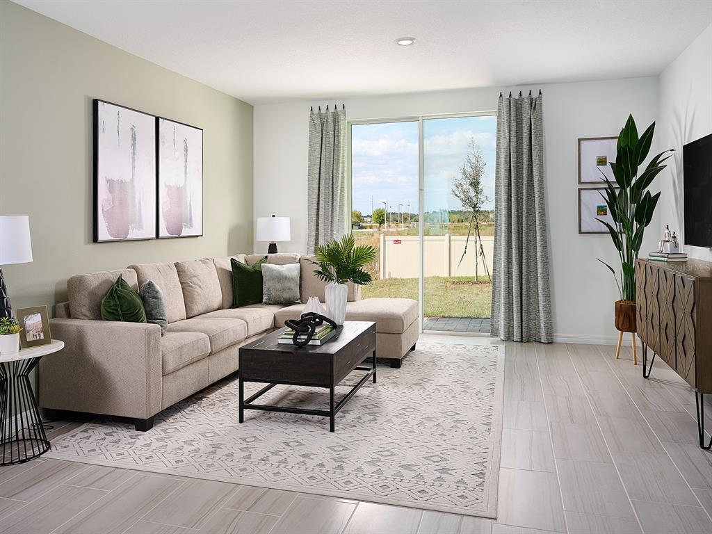 A living room features a beige sectional sofa, a dark coffee table, and a sliding door — 3960 GIORGIO DRIVE, WINTER HAVEN, FL