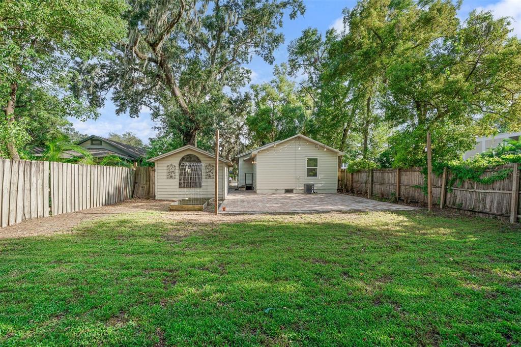 A backyard features a grassy lawn, a paved patio, a small shed, and wooden fencing — 1615 E CONCORD STREET, ORLANDO, FL
