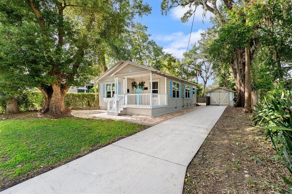 A light-colored single-story house with a front porch, blue shutters, and a long concrete driveway — 1615 E CONCORD STREET, ORLANDO, FL