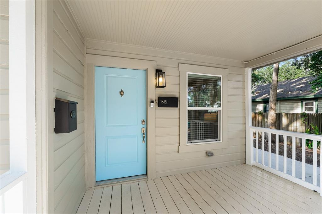 A covered front porch features a light blue door, a black mailbox, and white railings — 1615 E CONCORD STREET, ORLANDO, FL