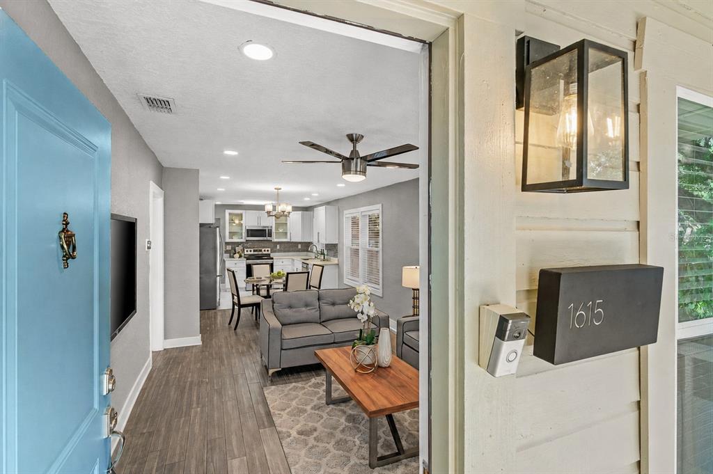 A view from an open front door looking into a living room and kitchen area — 1615 E CONCORD STREET, ORLANDO, FL
