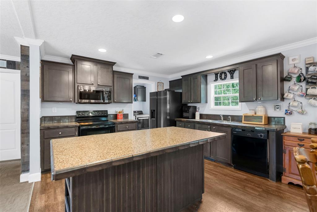 A kitchen with dark wood cabinets, a central island, and a mug rack on the wall — 17155 DALBERG DRIVE, SPRING HILL, FL