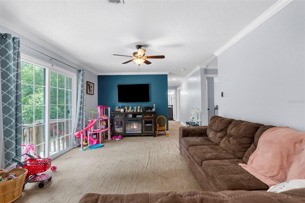A living room features a brown sofa, a dark wood media console, and a teal accent wall — 17155 DALBERG DRIVE, SPRING HILL, FL