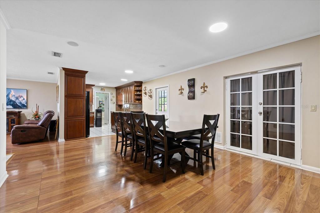 A dining area with a wooden table, chairs, and hardwood floors adjacent to a kitchen — 5809 N HALE AVENUE, TAMPA, FL