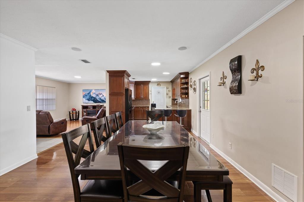 A dining area with a large wooden table leads into an open kitchen and living room — 5809 N HALE AVENUE, TAMPA, FL