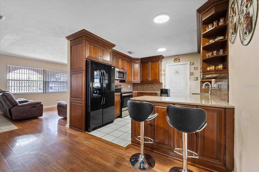 A kitchen with wood cabinets, black appliances, and a breakfast bar with two stools — 5809 N HALE AVENUE, TAMPA, FL