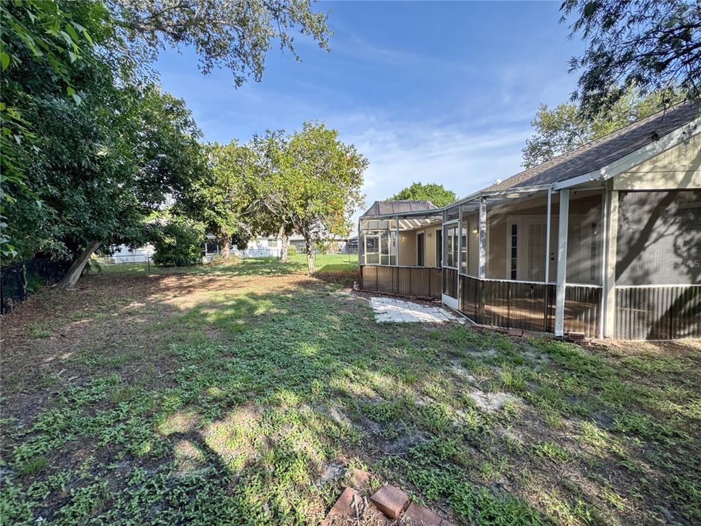 A backyard view showing a screened-in patio attached to a house with a grassy lawn — 3174 57TH AVENUE CIRCLE E, BRADENTON, FL