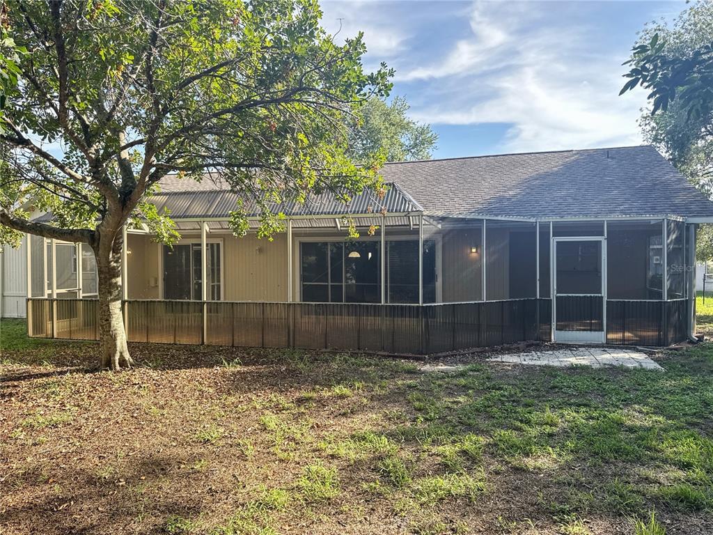 The exterior of a house features a large screened-in porch and a grassy backyard — 3174 57TH AVENUE CIRCLE E, BRADENTON, FL
