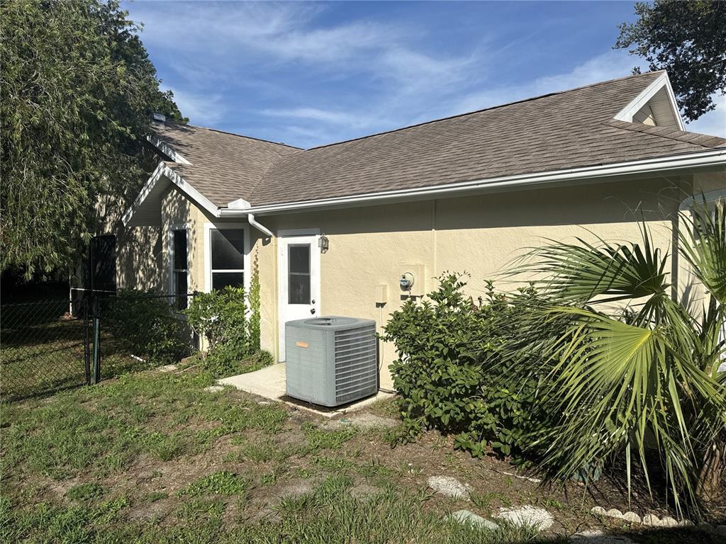 The exterior of a house features a tan stucco wall, a gray shingled roof, and an AC unit — 3174 57TH AVENUE CIRCLE E, BRADENTON, FL