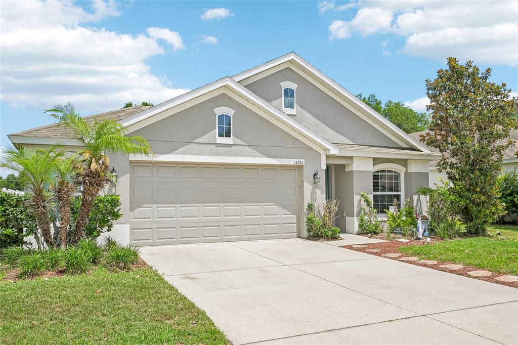 A single-story house with a two-car garage, gray stucco exterior, and a concrete driveway — 14284 FINSBURY DRIVE, SPRING HILL, FL