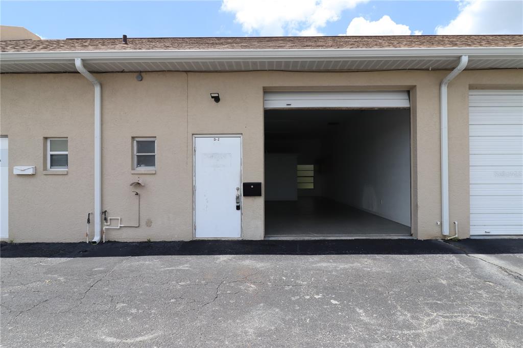 The exterior of a commercial unit features a white entry door and an open bay — 18350 PAULSON DRIVE UNIT D-2, PORT CHARLOTTE, FL