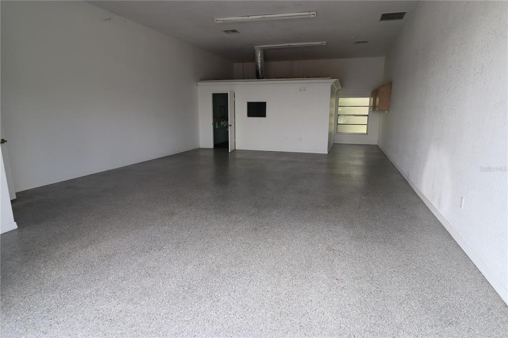 An empty commercial space features white walls, a gray speckled floor, and a small office — 18350 PAULSON DRIVE UNIT D-2, PORT CHARLOTTE, FL