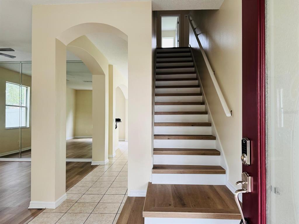 An empty room with beige walls, light-colored tile flooring, and a ceiling fan — 13621 TETHERLINE TRAIL, ORLANDO, FL