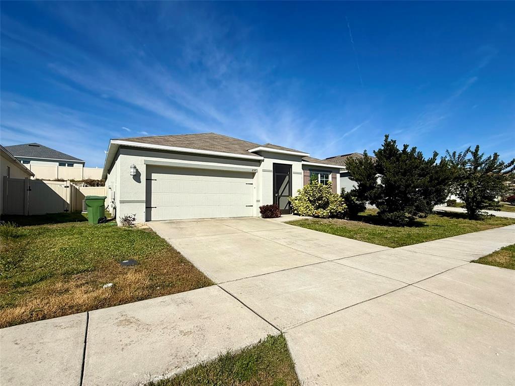A single-story house with a two-car garage and a concrete driveway at sunset — 257 MEADOWBROOK BOULEVARD, WINTER HAVEN, FL
