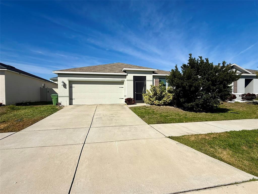 A single-story house with a two-car garage, concrete driveway, and a small front yard — 257 MEADOWBROOK BOULEVARD, WINTER HAVEN, FL