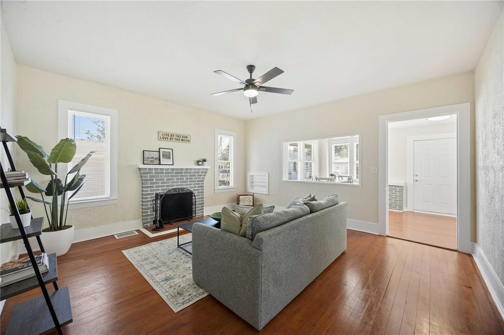 A living room features a gray brick fireplace, hardwood floors, and a gray sofa — 2710 3RD AVENUE W, BRADENTON, FL