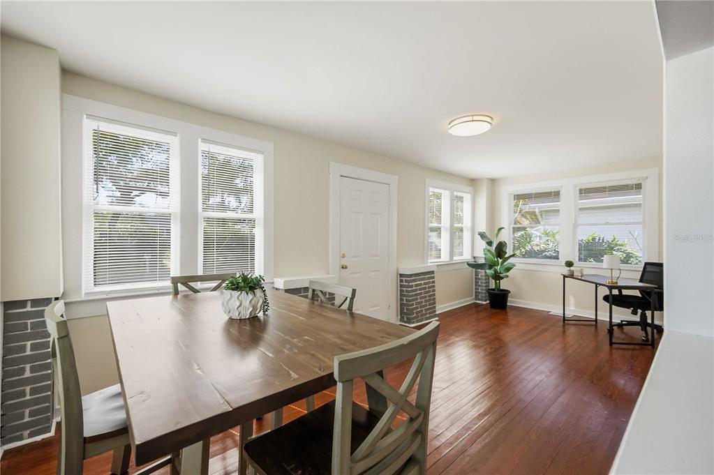 A dining room with hardwood floors, a wooden table, and a desk near windows — 2710 3RD AVENUE W, BRADENTON, FL