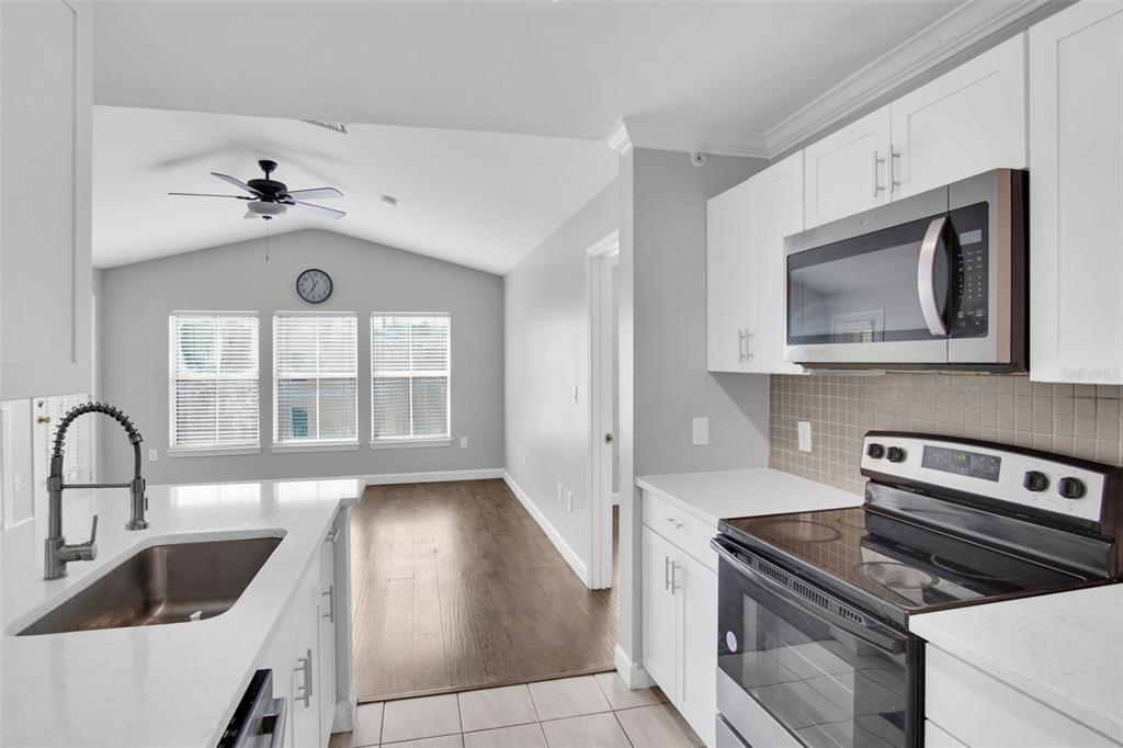 A living room with wood-look flooring, a vaulted ceiling, and an open kitchen island — 18245 BRIDLE CLUB DRIVE, TAMPA, FL