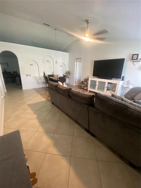 A living room with tile flooring, a large sectional sofa, and arched wall niches — 5287 SUNSET CANYON DRIVE, KISSIMMEE, FL