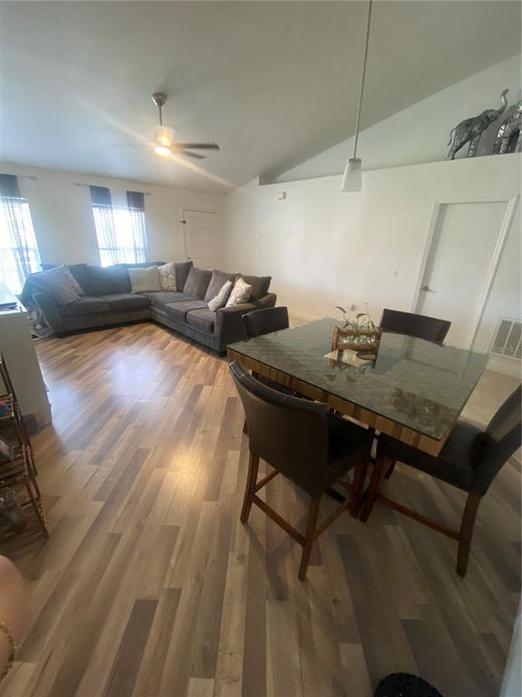 A living and dining area features wood-look flooring, a sectional sofa, and a glass-topped table — 5287 SUNSET CANYON DRIVE, KISSIMMEE, FL