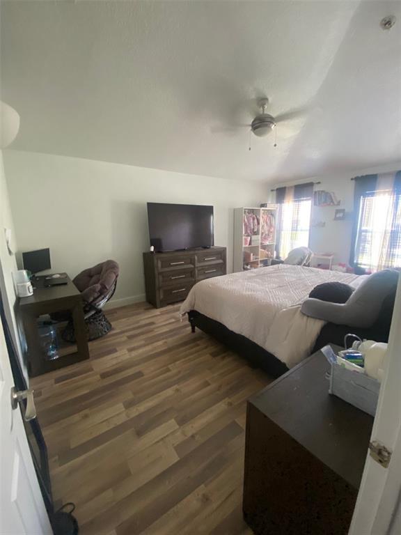A bedroom features wood-look flooring, a bed, a desk, a dresser with a television, and windows — 5287 SUNSET CANYON DRIVE, KISSIMMEE, FL