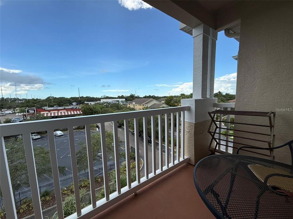 A balcony with a white railing overlooks a parking lot and surrounding buildings — 1216 S MISSOURI AVENUE UNIT 427, CLEARWATER, FL