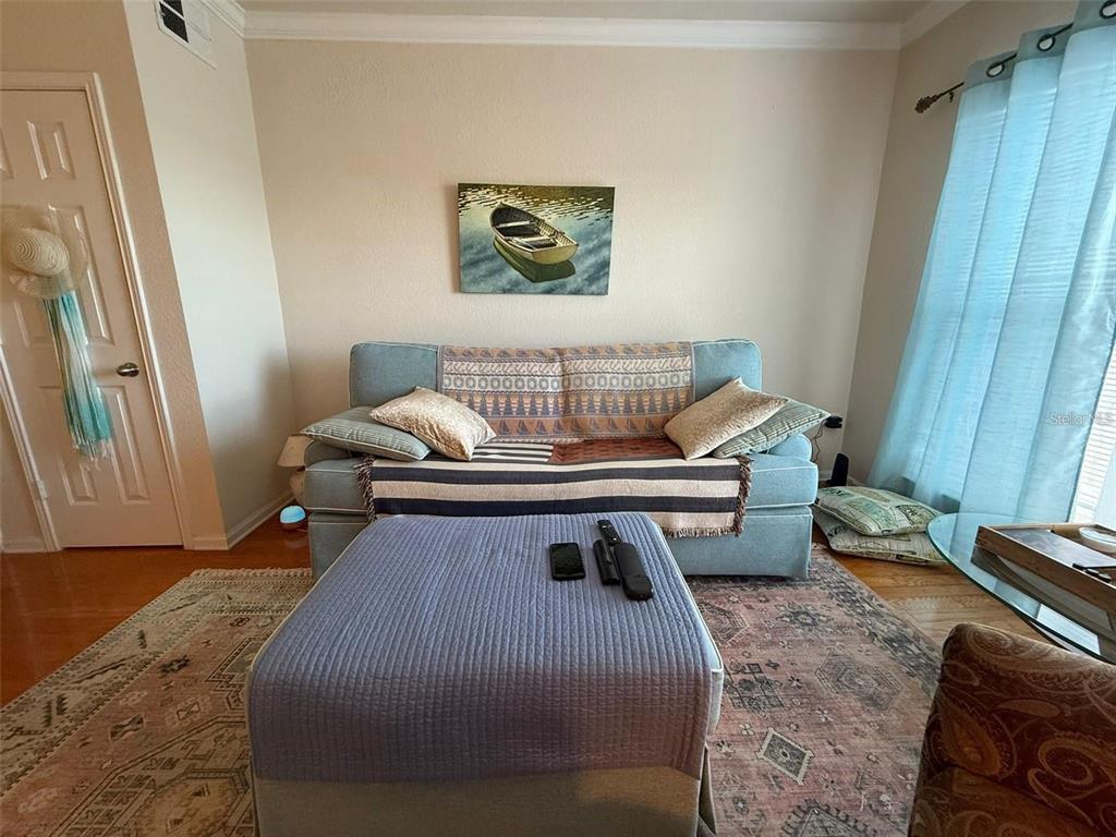 A living room features a blue sofa, a matching ottoman, and a boat wall painting — 1216 S MISSOURI AVENUE UNIT 427, CLEARWATER, FL
