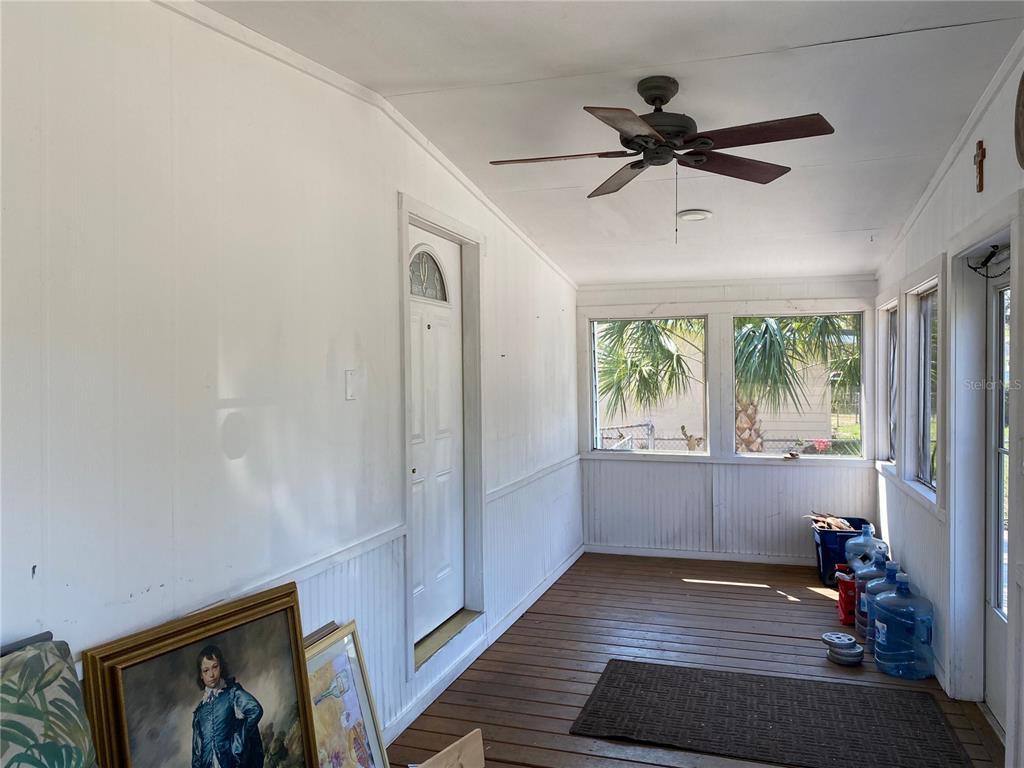A sunroom with white paneled walls, a wooden floor, a ceiling fan, and large windows — 313 S OBSERVATORY DRIVE, ORLANDO, FL