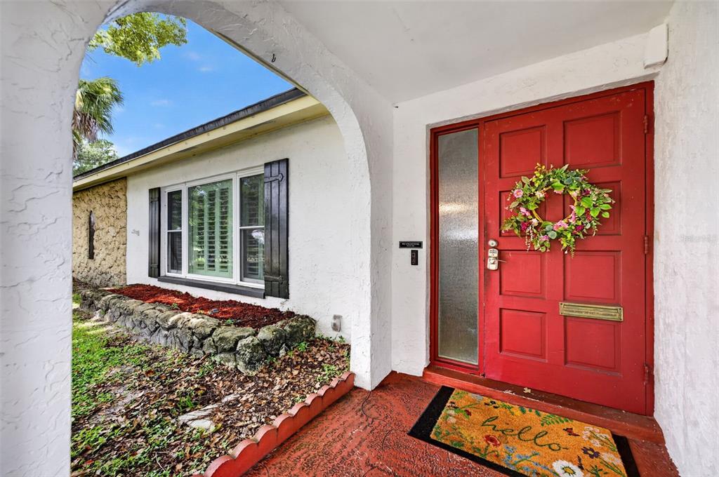 A red front door with a floral wreath sits under a white arched entryway — 2211 KING RICHARDS COURT, WINTER PARK, FL