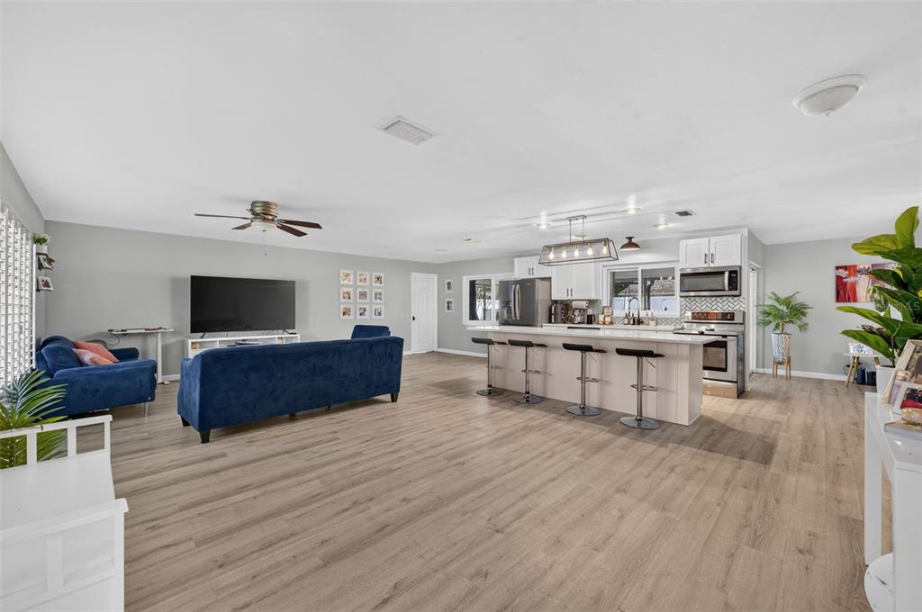 An open-concept living room and kitchen featuring wood-look flooring, a blue sofa, and island seating — 2211 KING RICHARDS COURT, WINTER PARK, FL