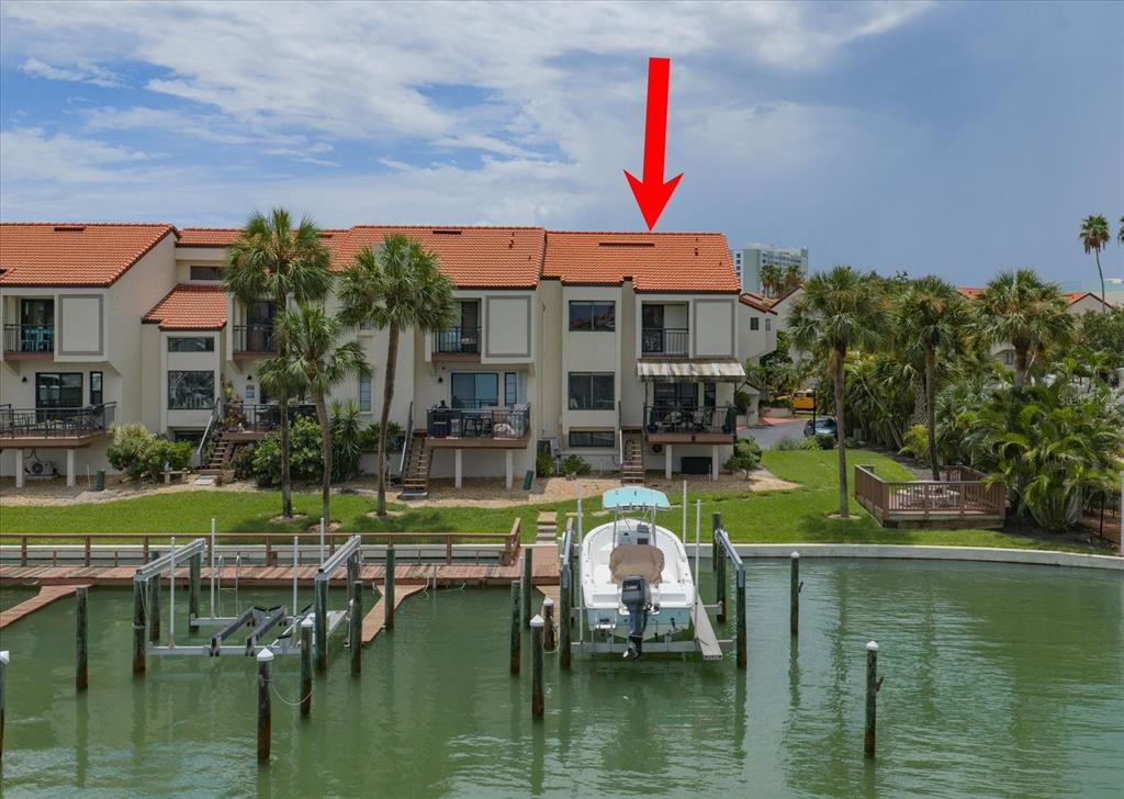 An exterior view of a multi-story waterfront townhouse complex with a red tile roof — 240 WINDWARD PSGE UNIT 401, CLEARWATER BEACH, FL