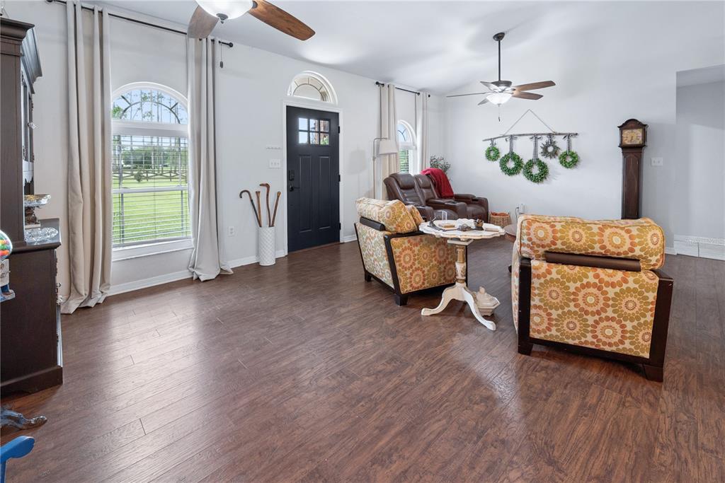 A living room features wood-look flooring, a black front door, and patterned armchairs — 11255 W COUNTY ROAD 18, LAKE BUTLER, FL