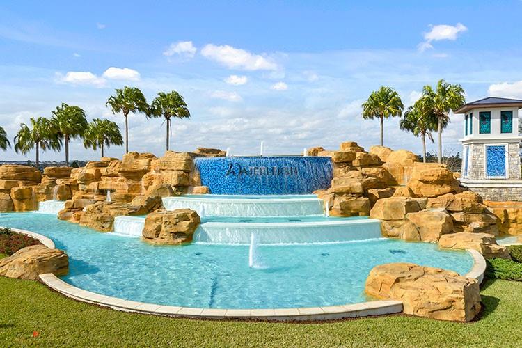 A tiered stone waterfall fountain with blue tile accents sits in front of palm trees — 16816 HOBE SOUND COURT, WINTER GARDEN, FL
