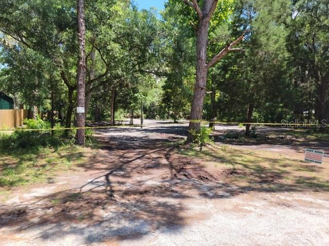 A wooded, undeveloped residential lot features a dirt clearing marked by yellow caution tape — 177 GLADYS AVENUE, INGLIS, FL