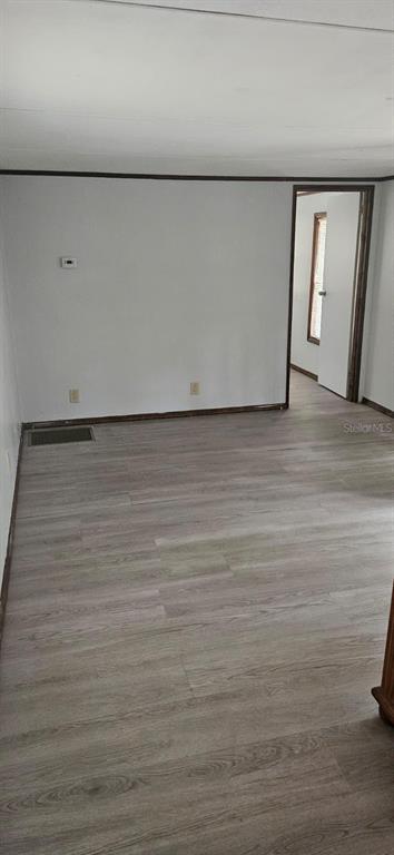 A room with light wood-look flooring, white walls, and a doorway leading to another room — 3111 NE 167 PLACE, CITRA, FL