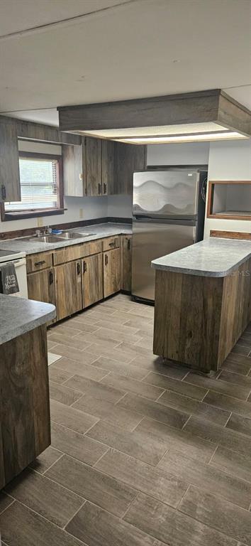 A kitchen features wood-look cabinets, gray countertops, stainless steel appliances, and wood-patterned tile flooring — 3111 NE 167 PLACE, CITRA, FL
