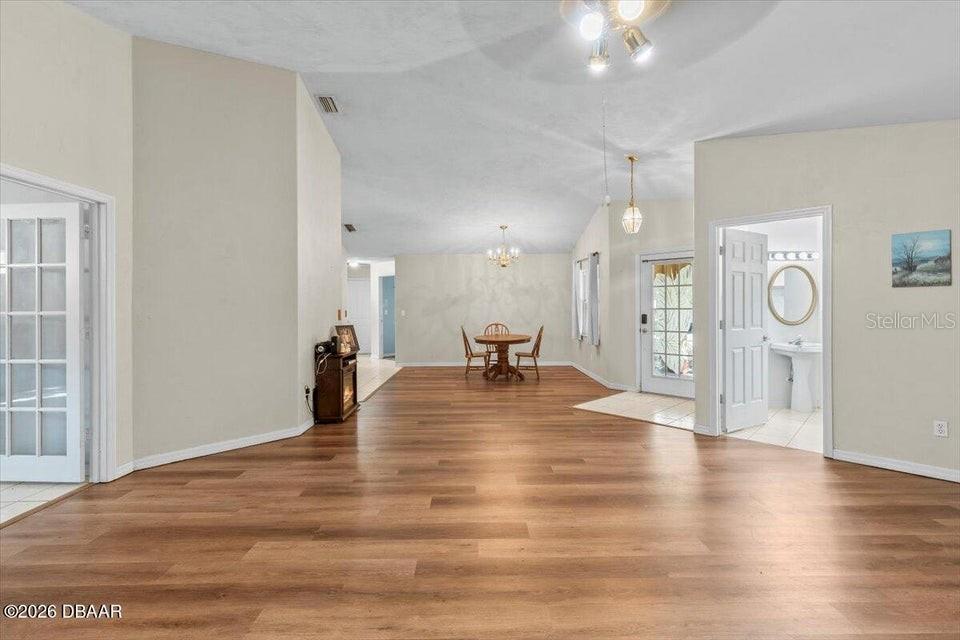 A spacious living area features wood-look flooring, vaulted ceilings, and a dining set — 29 SHERRINGTON DRIVE, ORMOND BEACH, FL