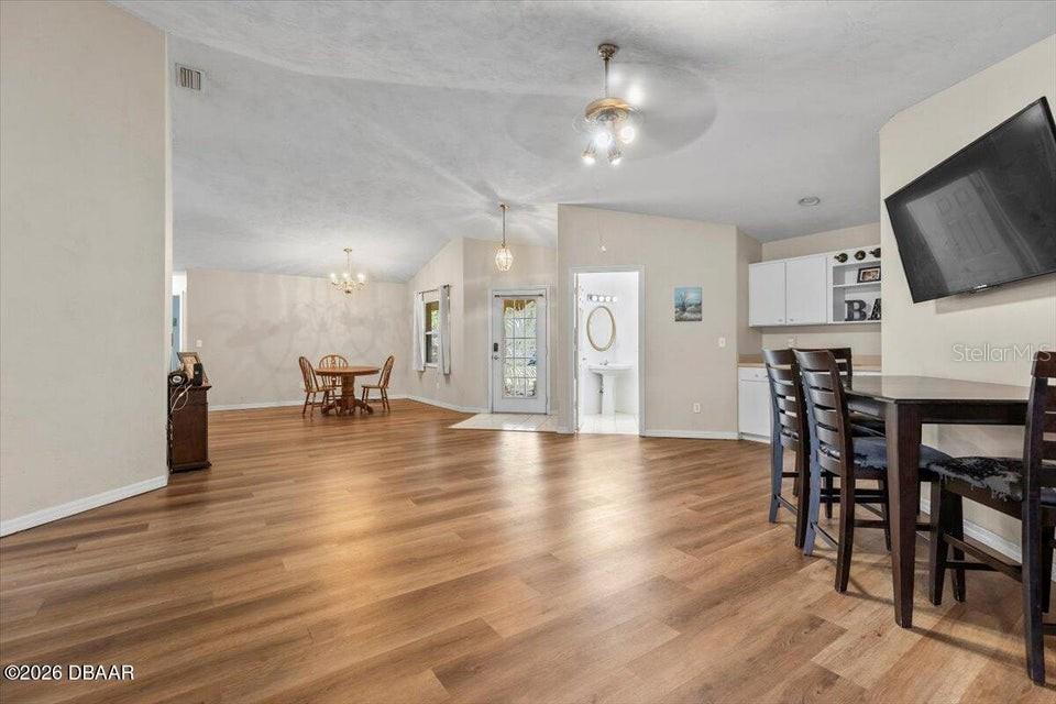An open-concept dining and living area features wood-look flooring and a ceiling fan — 29 SHERRINGTON DRIVE, ORMOND BEACH, FL