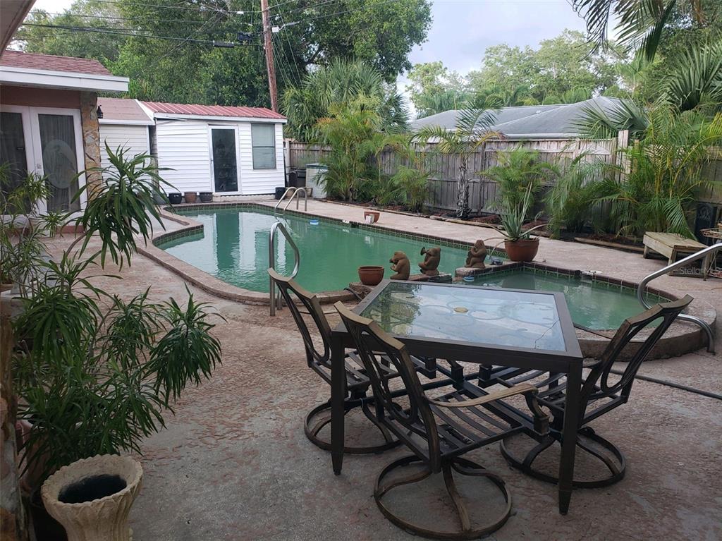 A backyard patio features a dining set, a swimming pool, and a small attached spa — 8665 MOCKINGBIRD LANE, SEMINOLE, FL