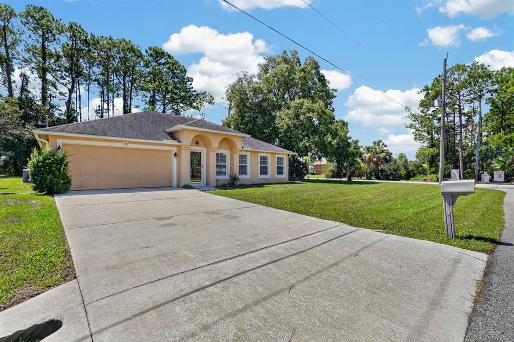 A single-story house with a tan stucco exterior, a two-car garage, and a concrete driveway — 99 PICKERING DRIVE, PALM COAST, FL