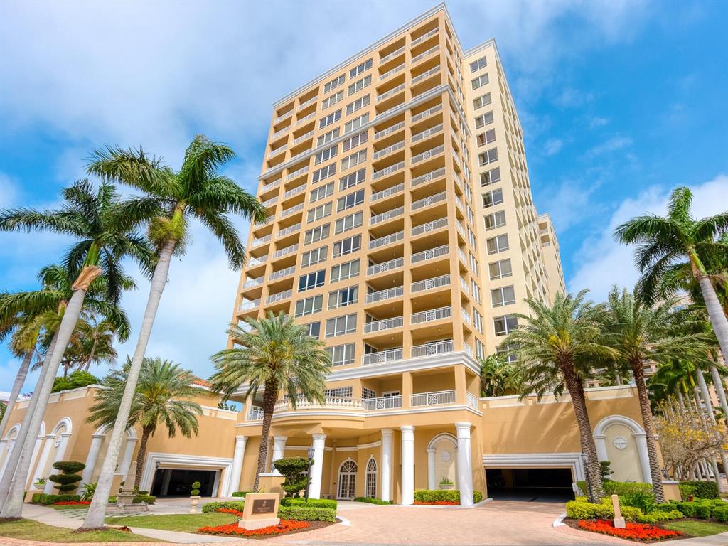 A tall, tan high-rise residential building features multiple balconies and palm trees in the foreground — 35 WATERGATE DRIVE UNIT 906, SARASOTA, FL
