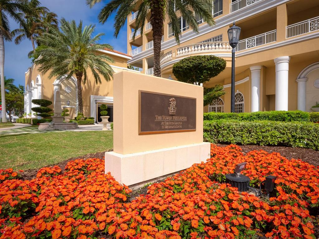 A sign for The Tower Residences stands in front of a multi-story building with landscaping — 35 WATERGATE DRIVE UNIT 906, SARASOTA, FL