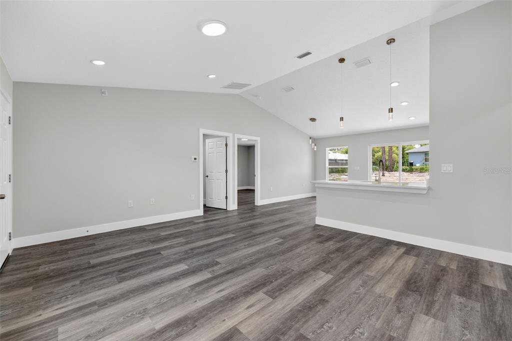 An open-concept living area features gray walls, dark wood-look flooring, and a kitchen breakfast bar — 13155 SW 70TH COURT, OCALA, FL