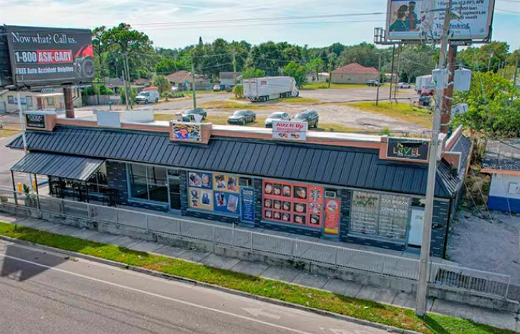 An aerial view of a commercial building with a dark metal roof and storefront signage — 9002 N 40TH, TAMPA, FL