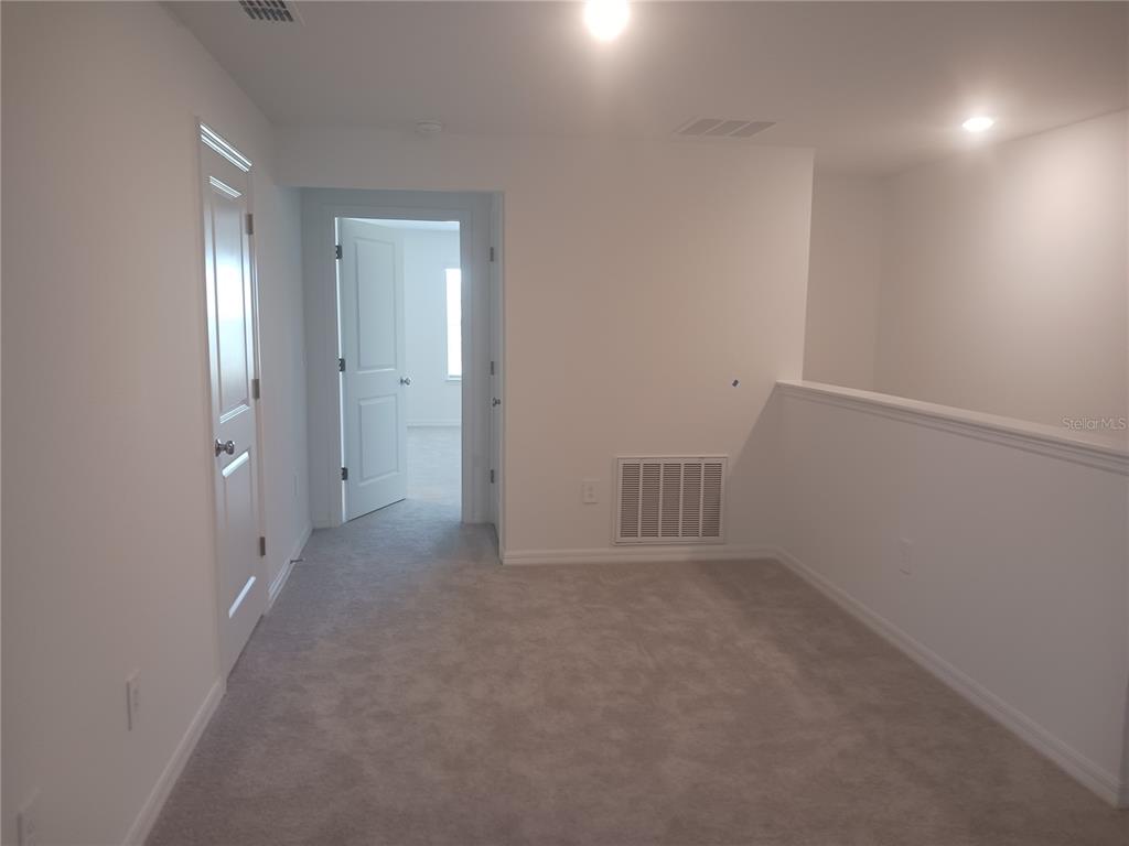 A carpeted loft area features white walls, recessed lighting, a vent, and two interior doors — 8607 TROPICAL AIRE LANE, PARRISH, FL