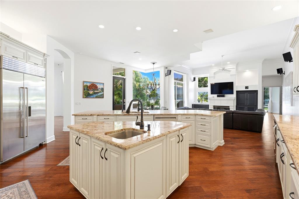 A kitchen with white cabinetry, granite countertops, and hardwood floors opens to a living area — 3459 WOODRIDGE PARKWAY, PALM HARBOR, FL