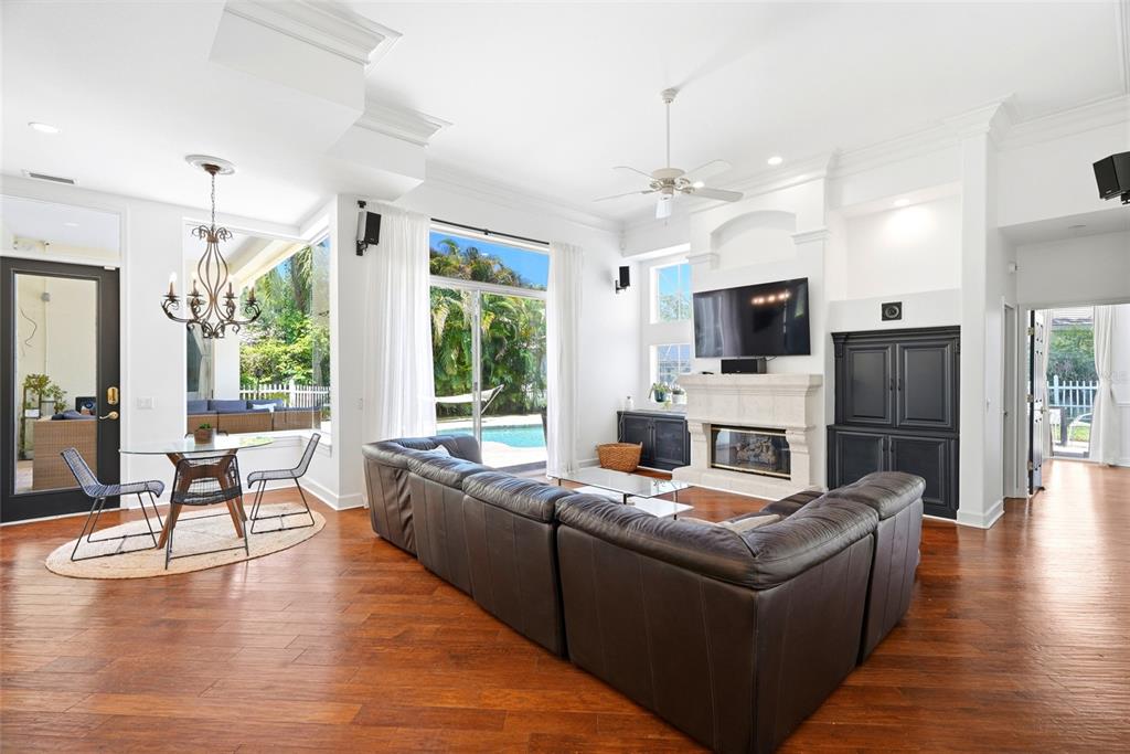 A living room with a dark leather sectional, fireplace, and dining area overlooking a pool — 3459 WOODRIDGE PARKWAY, PALM HARBOR, FL
