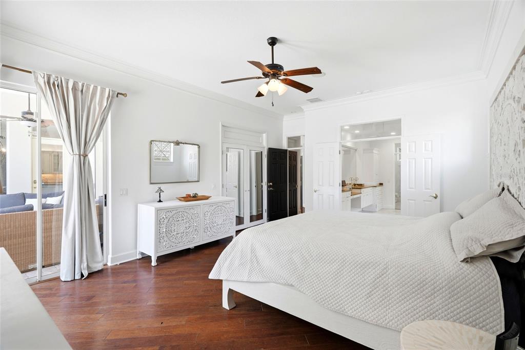 A bedroom with white walls, dark wood floors, a ceiling fan, and an attached bathroom — 3459 WOODRIDGE PARKWAY, PALM HARBOR, FL