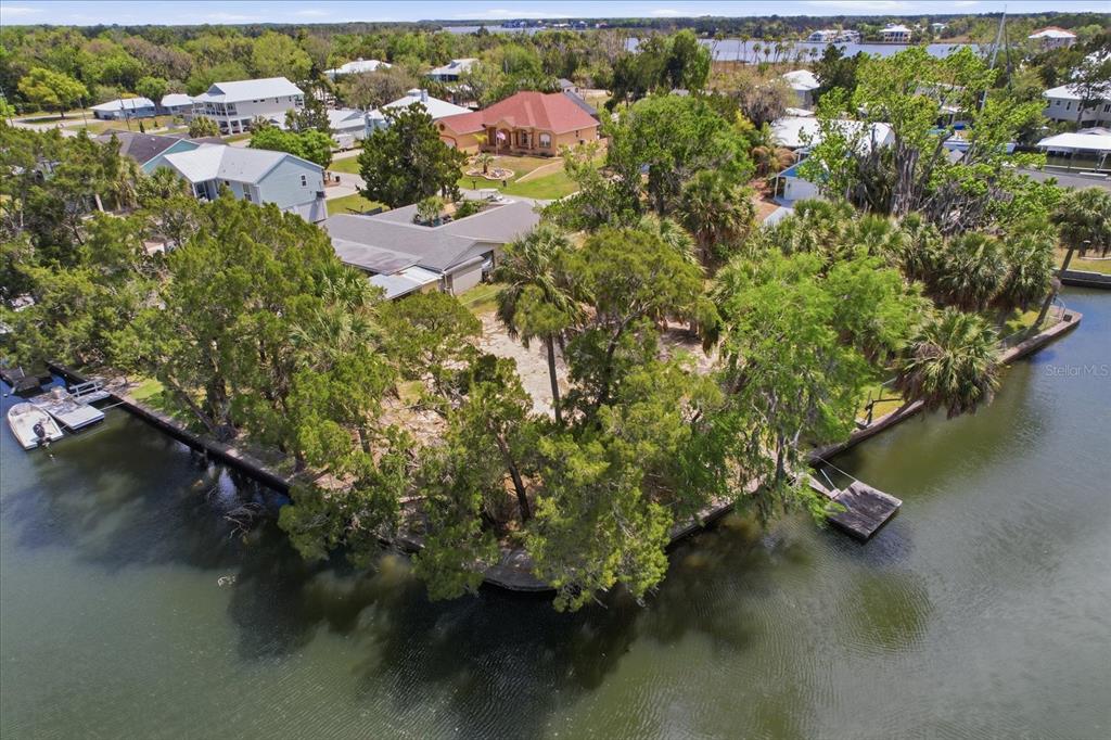 A vacant waterfront lot features a concrete seawall, a chain-link fence, and several mature trees — 1941 NW 16TH STREET, CRYSTAL RIVER, FL